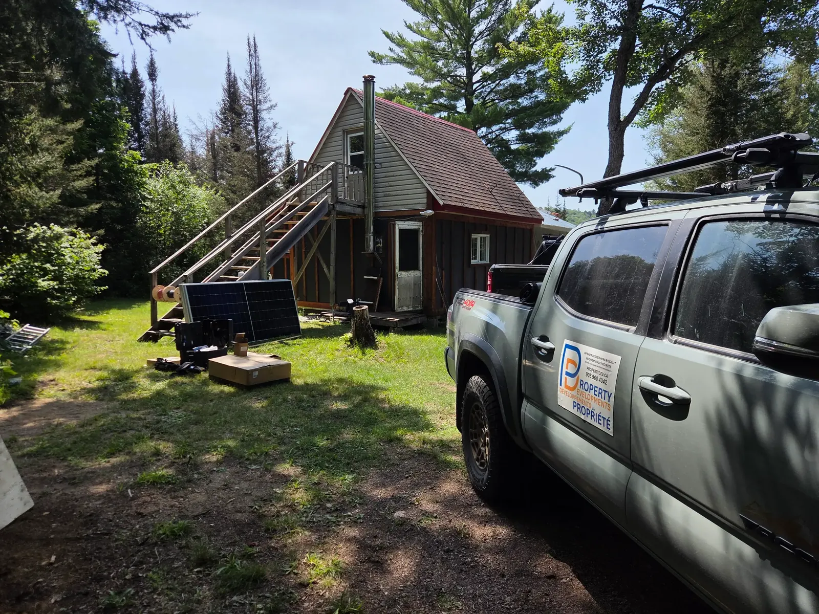 Property Developments vehicle at a remote cabin with solar equipment staged nearby