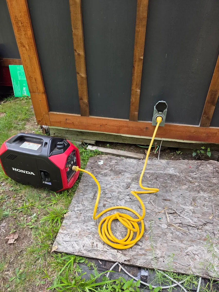 Portable generator connected to an exterior inlet at a rural cabin.