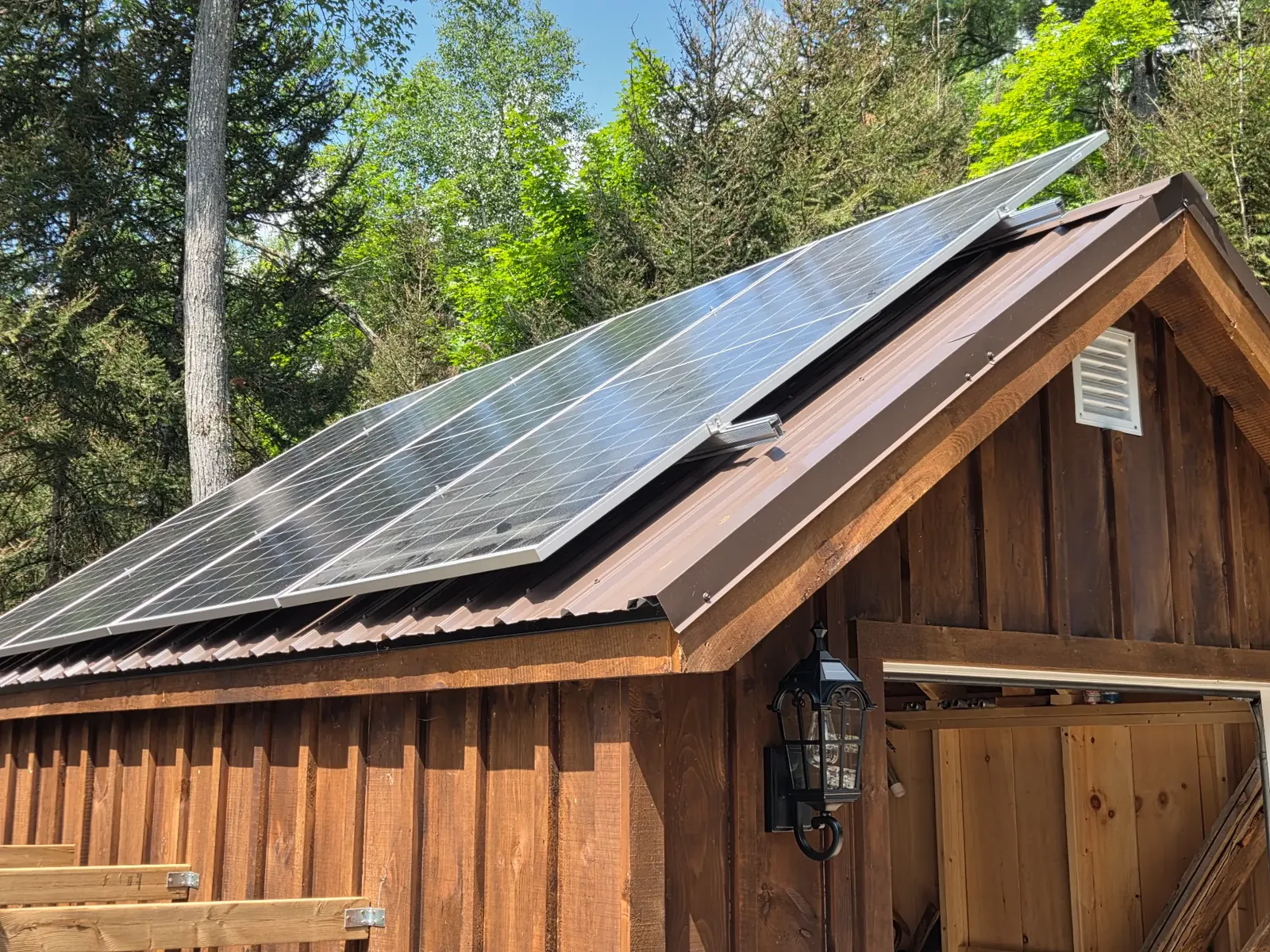 Solar panels on the roof of a small wooden building in a forest.
