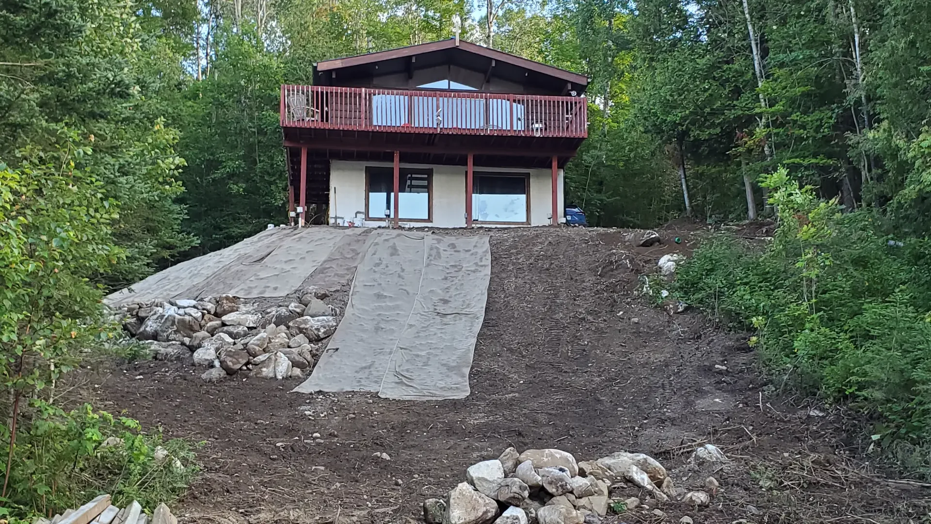 Remote cabin property with graded slope, stonework, and woodland terrain